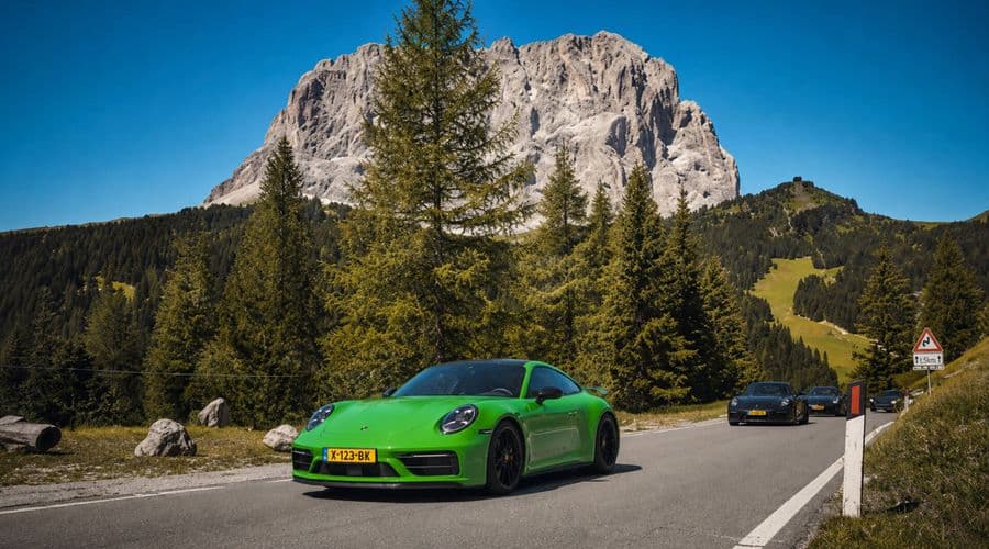 Groene Porsche 911 op een bergweg in de Dolomieten