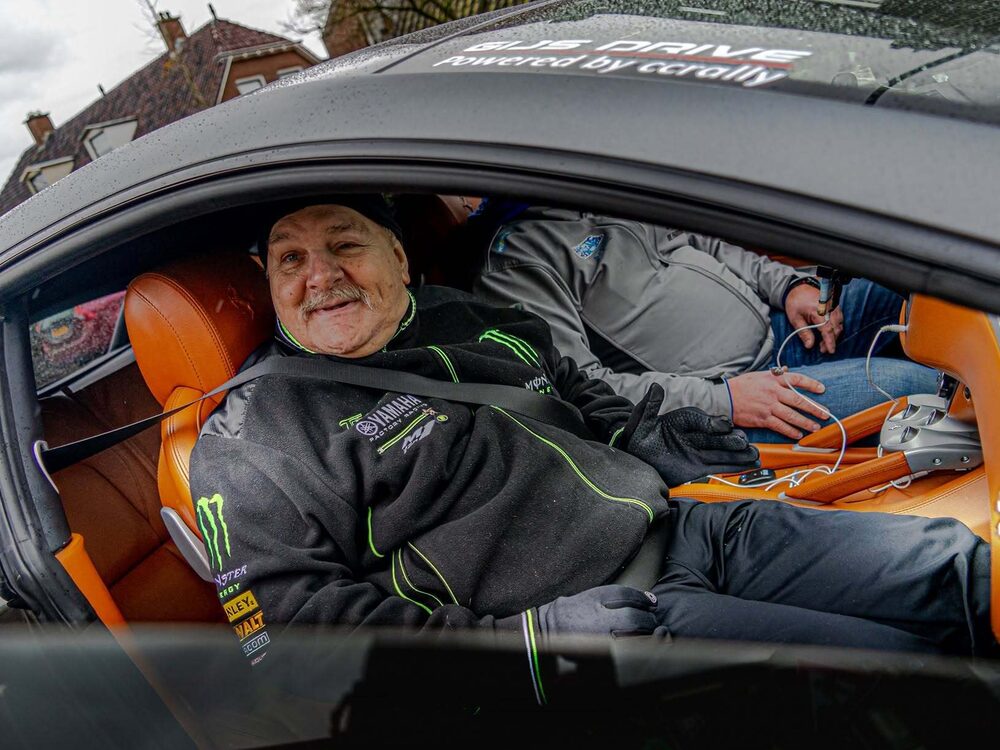 Deelnemer lacht vanaf de bijrijdersstoel van een supercar