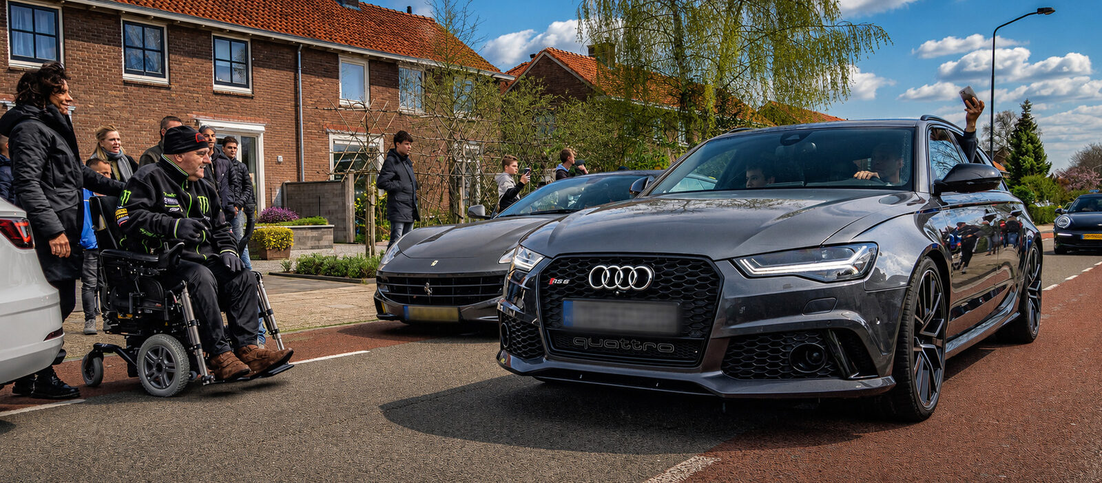 Deelnemer in een rolstoel kijkt toe hoe de auto’s van de goede-doel rally de straat in rijden