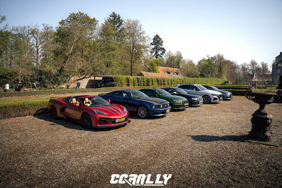 Sports cars lined up on the gravel at a castle during a supercar rally