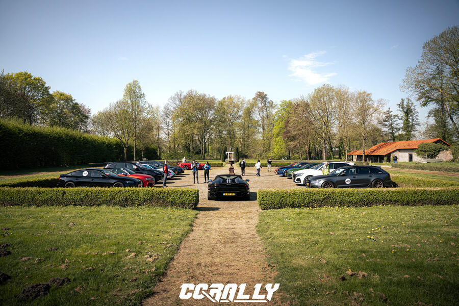 A supercar on the path between the hedges of a castle garden, before the start of the drive
