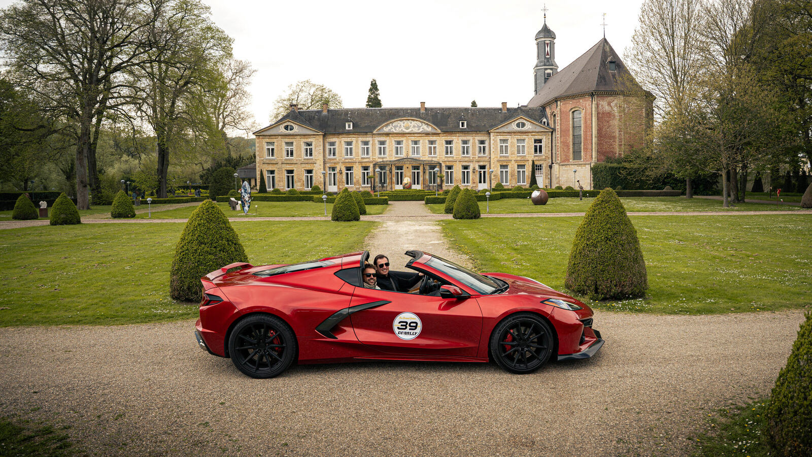 Red Corvette with a rally number on the gravel path of a castle garden during a CCRally supercar rally