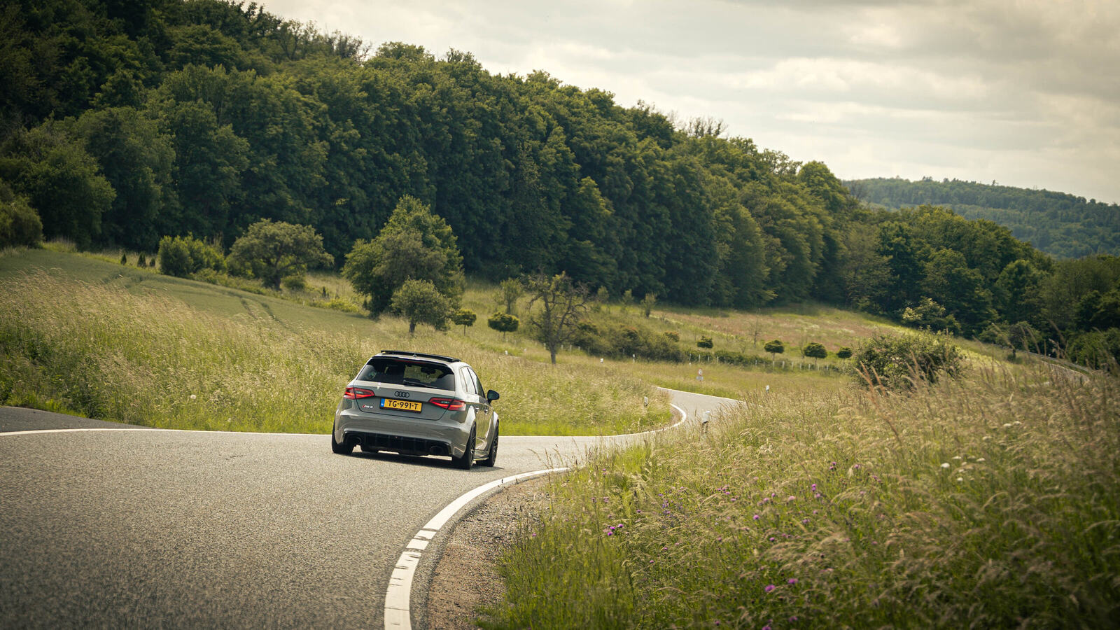 Sports car on a winding road through hilly countryside during a road trip