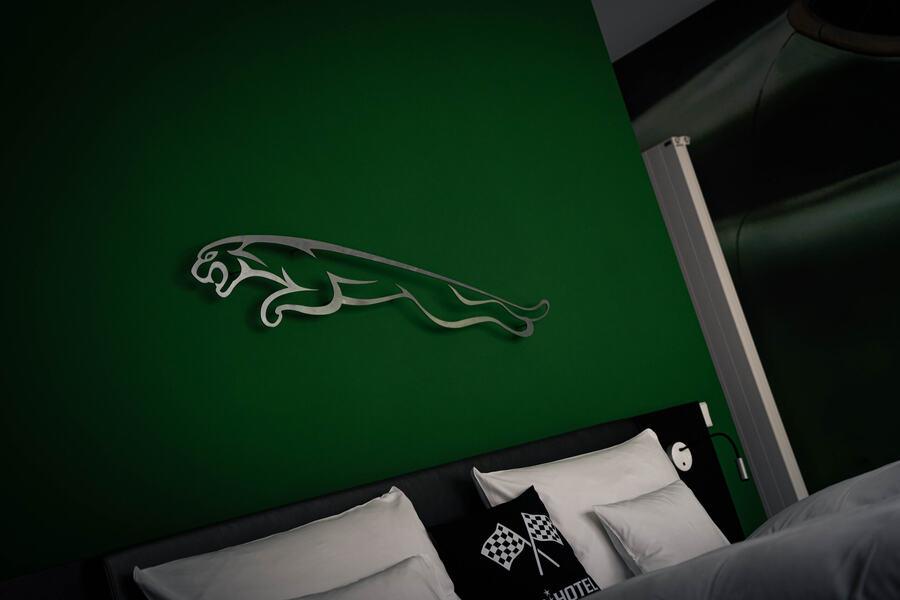 Hotel room with a Jaguar emblem and chequered-flag cushions during a multi-day drive through Europe