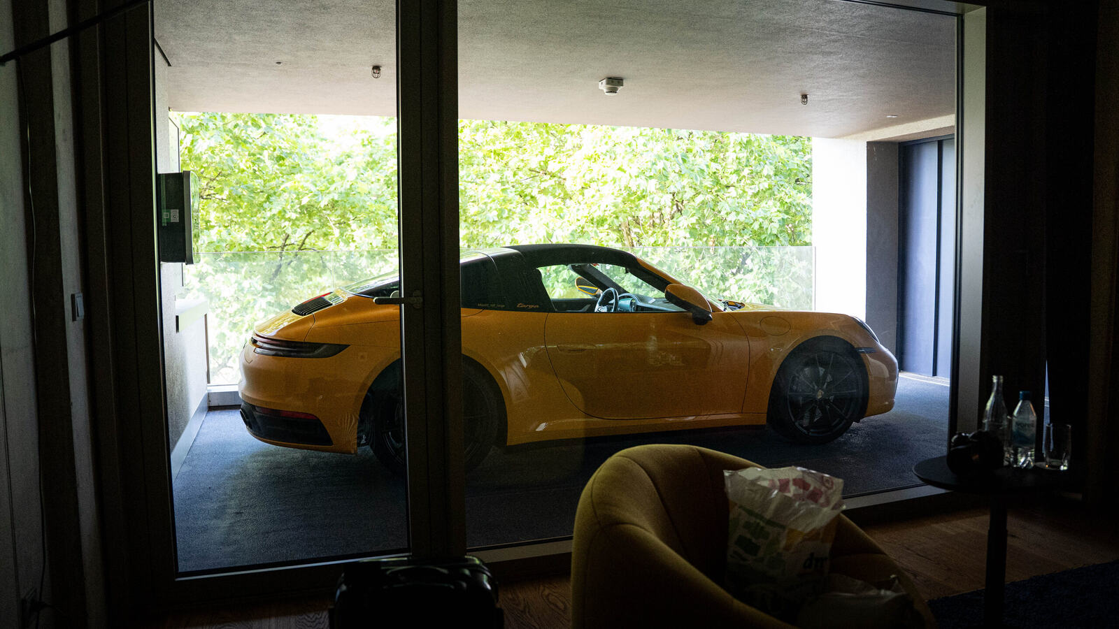 Yellow Porsche 911 convertible in a garage, seen through a window, during a Porsche road trip